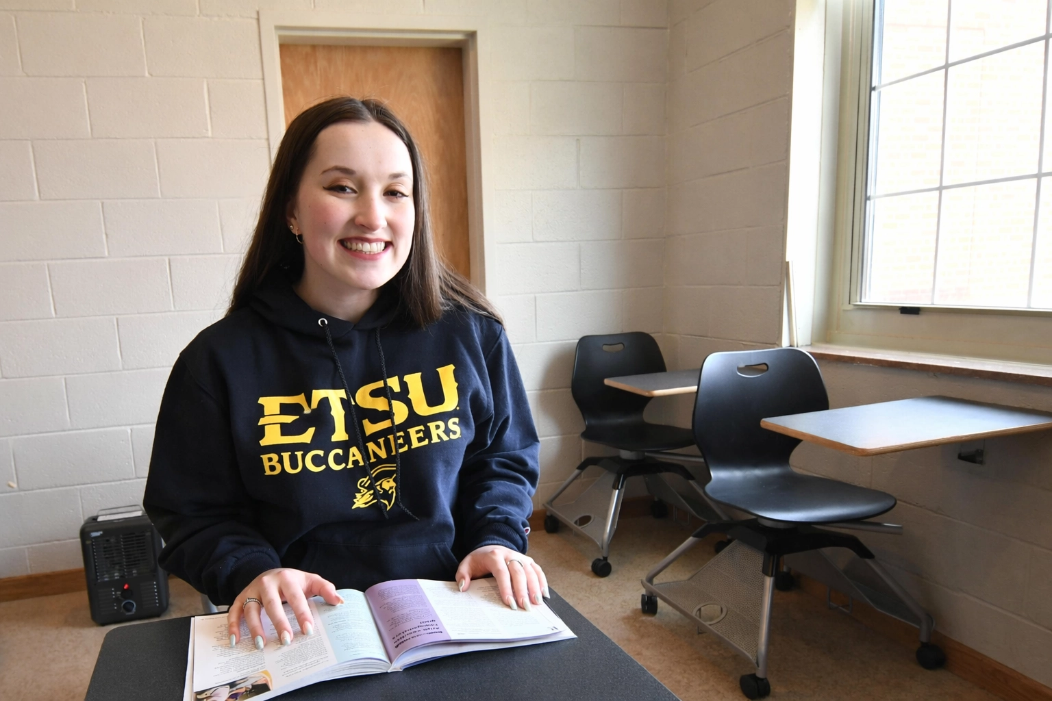 Laura Clifton studies from an open textbook while seated in a classroom at East Tennessee State University.
