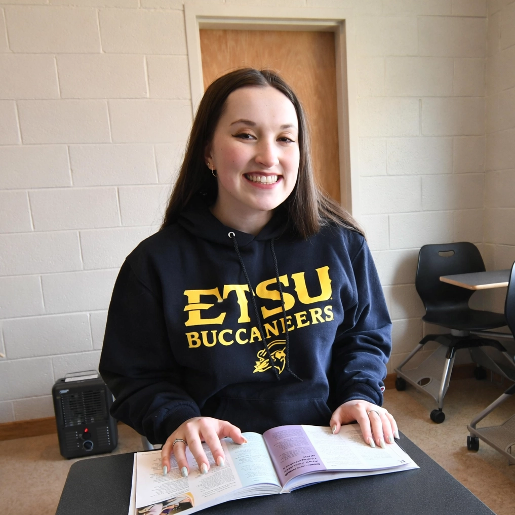 Laura Clifton studies from an open textbook while seated in a classroom at East Tennessee State University.